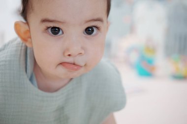 Evde çocuklarla oynayan sevimli, mutlu bir bebek. Oturma odasında yerde oturuyor..