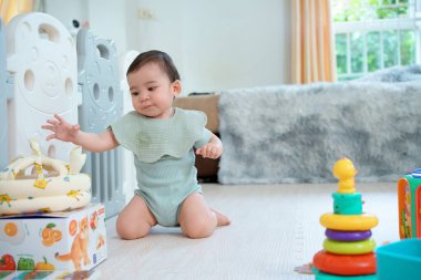 Evde çocuklarla oynayan sevimli, mutlu bir bebek. Oturma odasında yerde oturuyor..