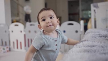 Bebek kalkmaya çalışıyor, ilk adımlarını atıyor, kanepeye yaslanıyor. Mutlu aile çocuğu hayali konsepti. Yaşam tarzı bebek ilk adımlarını içeride atıyor..