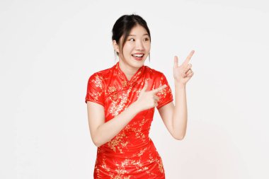 Geleneksel Cheongsam Qipao elbisesi giyen mutlu Asyalı kadın beyaz arka planda izole edilmiş fotokopi alanını işaret ediyor. Mutlu Çin Yeni Yılı.