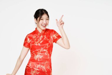 Geleneksel Cheongsam Qipao elbisesi giyen mutlu Asyalı kadın beyaz arka planda izole edilmiş fotokopi alanını işaret ediyor. Mutlu Çin Yeni Yılı.