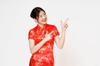 Geleneksel Cheongsam Qipao elbisesi giyen mutlu Asyalı kadın beyaz arka planda izole edilmiş fotokopi alanını işaret ediyor. Mutlu Çin Yeni Yılı.