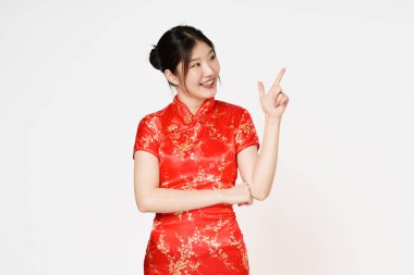 Geleneksel Cheongsam Qipao elbisesi giyen mutlu Asyalı kadın beyaz arka planda izole edilmiş fotokopi alanını işaret ediyor. Mutlu Çin Yeni Yılı.