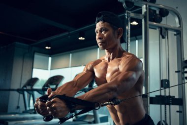 Sportif Asyalı adam spor salonunda kol ve omuz kasları için egzersiz yapıyor. Spor salonunda spor yapmak..