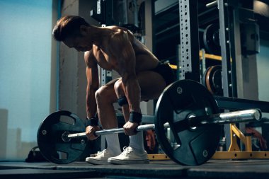 Sportif vücut geliştirici ya da halterci spor salonunda halterle ağırlık kaldırma egzersizi yapıyor. Spor salonunda spor yapmak..