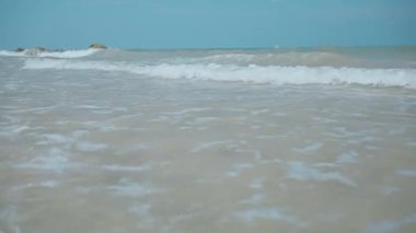 Köpüklü deniz dalgaları kumsala gelir güneşli yaz mevsiminde güzel.