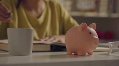 Asya 'lı bir kadının kumbaraya bozuk para attığı yakın plan..