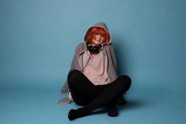 Mavi arka planda kulaklıkları olan şık bir genç kız..