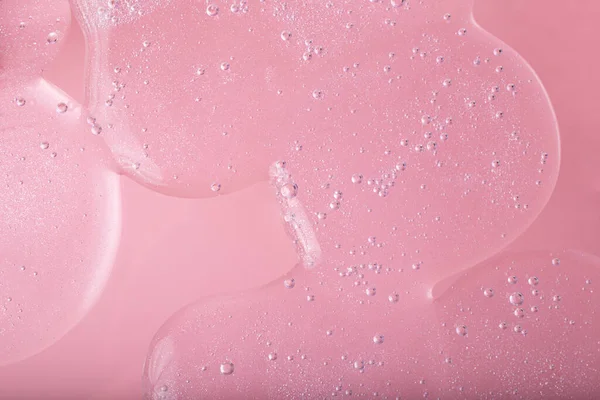 Pembe arka planda köpüklü yapısıyla sıvı kozmetik jelinin üst görüntüsü. Kozmetik modelleme kadar iyi..