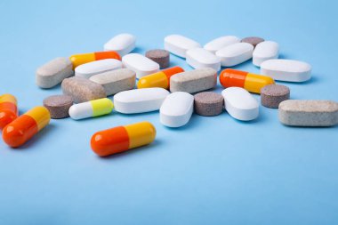 Mavi arkaplanda farklı hapların ön görünümü, metin için kopyalama alanı.