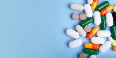 Mavi arkaplanda farklı hapların üst görünümü, metin için alanı kopyala. Negatif alanlı büyük afiş.