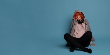 Mavi arka planda kulaklıklı şık bir genç kızın fotoğrafı. Negatif afişi olan büyük bir afiş..