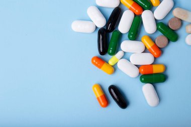 Mavi arkaplanda farklı hapların üst görünümü, metin için alanı kopyala. Negatif alanlı büyük afiş.