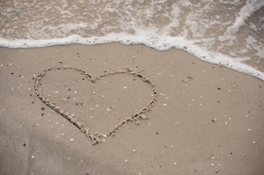 Heart drawing on sea sand,natural background.