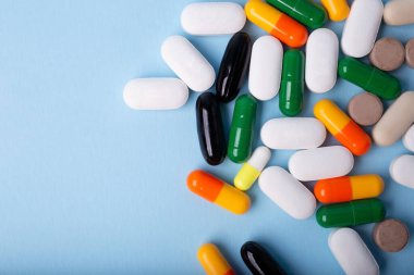 Mavi arkaplanda farklı hapların üst görünümü, negatif boşluklu pankart.