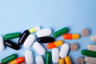 Mavi arka planda farklı hapların ön görünümü, negatif boşluklu pankart.