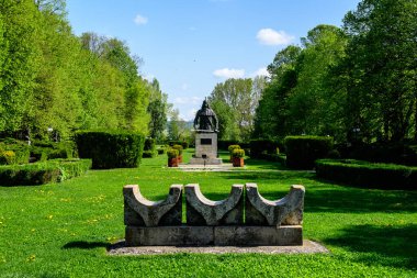 Romanya 'nın Targoviste şehrinden, beyaz bulutlar ve mavi gökyüzü ile güneşli bir bahar gününde, Chindia Park' taki (Parcul Chindia) canlı yeşil ağaçlar ve çimlerle kaplı manzara