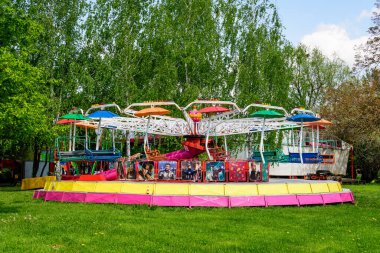 Targoviste, Romanya, 1 Mayıs 2022: Güneşli bir bahar gününde Parcul Chindia Parkı 'nda (Chindia Park) karışık plastik ve metalik oyuncaklar ile renkli çocuklar atlıkarınca