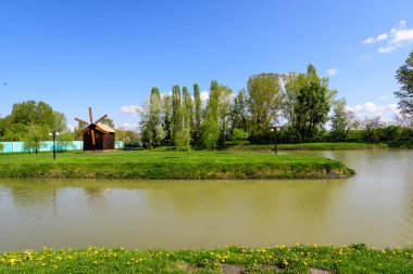 Romanya 'nın Targoviste kentinde bulunan Chindiei Parkı' ndan (Parcul Chindiei) küçük bir göl, güneşli bir bahar gününde beyaz bulutlar ve mavi gökyüzü