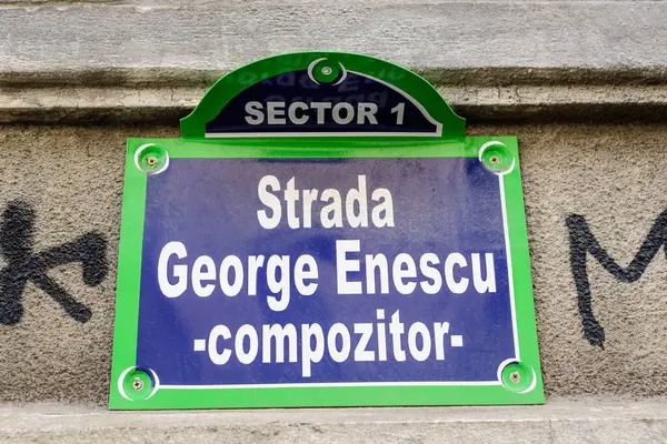 Beautiful vintage street sign showing Strada George Enescu (George Enescu Street) displayed on an street in the old city center of Bucharest, Romania, in a sunny day