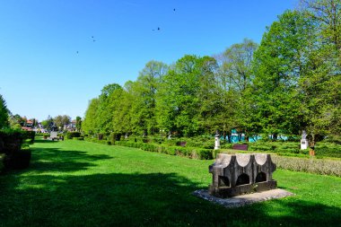 Romanya 'nın Targoviste şehrinden, beyaz bulutlar ve mavi gökyüzü ile güneşli bir bahar gününde, Chindia Park' taki (Parcul Chindia) canlı yeşil ağaçlar ve çimlerle kaplı manzara