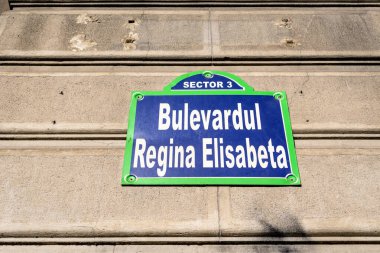 Bulevardul Regina Elisabeta 'yı (Regina Elisabeta Bulvarı) gösteren güzel bir klasik sokak tabelası, açık mavi gökyüzüyle güneşli bir günde Romanya' nın Bükreş kentinin eski şehir merkezinde bir sokakta sergilendi.