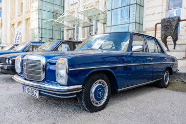 Bükreş, Romanya, 2 Ekim 2021: 1975 yılında üretilen bir canlı mavi Mercedes 220D (115W) klasik otomobil ve güneşli bir sonbahar gününde klasik araba koleksiyonları için bir sokakta park edildi