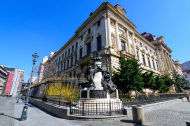 Bükreş, Romanya - 27 Mart 2021: Güneşli bir bahar gününde şehir merkezindeki tarihi bir binada Romanya Merkez Bankası 'nın (Banca Nationala a Romaniei, BNR) önündeki heykel