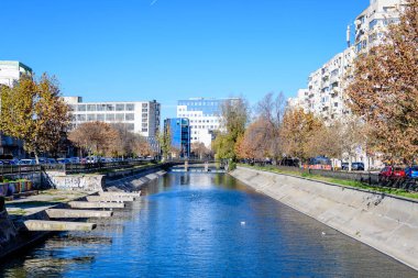 Bucharest, Romania, 20 November 2021: Modern buildings and offices near Dambovita river and cloudy blue sky in the center of the city, in a sunny autumn day