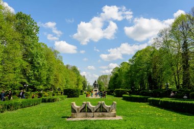 Targoviste, Romanya, 1 Mayıs 2022: Beyaz bulutlar ve mavi gökyüzü ile güneşli bir bahar gününde Chindia Park 'ta (Parcul Chindia) canlı yeşil ağaçlar ve çimlerle kaplı manzara
