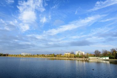 Romanya 'nın Bükreş kentinde, Linden Park' taki (Parcul Tei) ağaçlı manzara, güneşli bir sonbahar gününde beyaz bulutlar ve mavi gökyüzü