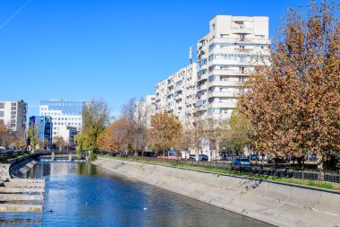 Bucharest, Romania, 20 November 2021: Modern buildings and offices near Dambovita river and cloudy blue sky in the center of the city, in a sunny autumn day