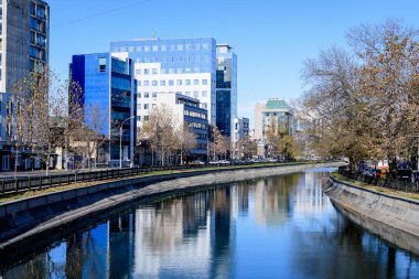 Bucharest, Romania, 20 November 2021: Modern buildings and offices near Dambovita river and cloudy blue sky in the center of the city, in a sunny autumn day