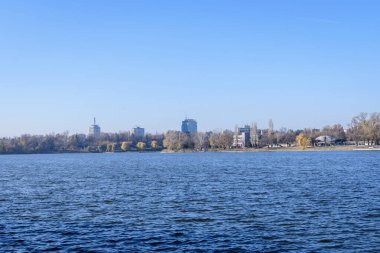 Bucharest, Romania, 21 November 2021: Landscape with trees and the lake in Floreasca Park (Parcul Floreasca), in Bucharest, Romania, in a sunny autumn day with white clouds and blue sky