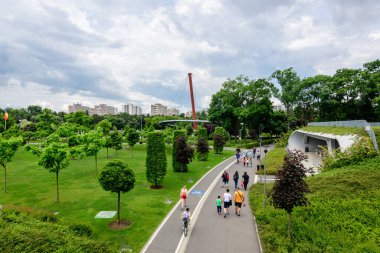 Bükreş, Romanya - 29 Mayıs 2021: Bulutlu bir yaz gününde, Drumul Taberei Parkı 'ndaki (Parcul Drumul Taberei) ara sokak ve canlı yeşil ağaçlarla çevrili manzara