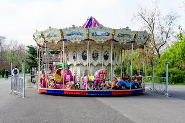 Bükreş, Romanya - 24 Nisan 2021: Parcul Tineretului (Gençlik Parkı) Parcul Tineretului 'de güneşli bir bahar gününde beyaz gökyüzü ile karışık plastik ve metalik oyuncak ve malzemelerle renkli çocuklar atlıkarınca