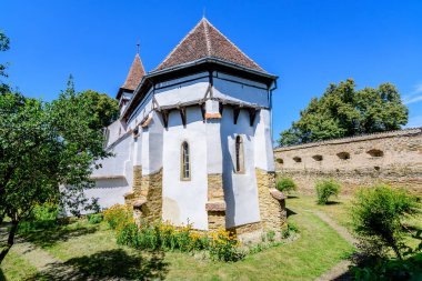 Old building of Saints Peter and Paul fortified Church (Biserica Sfintii Apostoli Petru si Pavel) in Cincsor village, near Fagaras in Transylvania (Transilvania) region, Romania, in a sunny summer day clipart