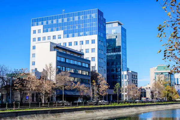 stock image Bucharest, Romania, 20 November 2021: Modern buildings and offices near Dambovita river and cloudy blue sky in the center of the city, in a sunny autumn day