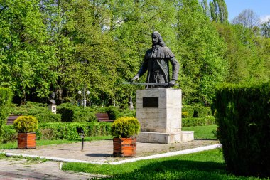 Romanya 'nın Targoviste şehrinden, beyaz bulutlar ve mavi gökyüzü ile güneşli bir bahar gününde, Chindia Park' taki (Parcul Chindia) canlı yeşil ağaçlar ve çimlerle kaplı manzara