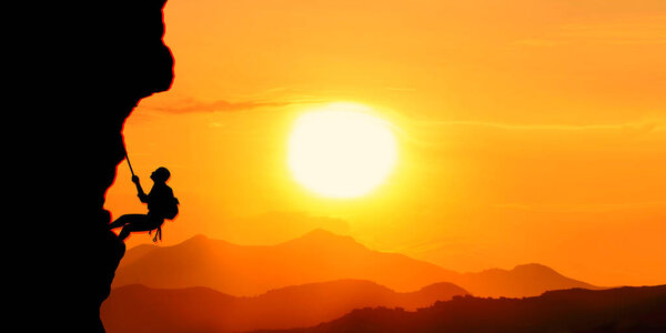 силуэт мужчины с рюкзаком на вершине горы