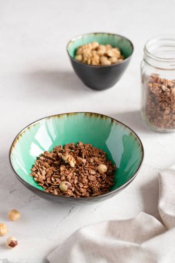 Ev yapımı fındıklı granola ve açık beton arka planda seramik bir kasede çikolata. Mısır gevreği. Sağlıklı yemek..