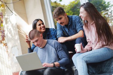 Dört arkadaş dışarıda bir merdivende oturmuş, bir çalışma seansına katılıyorlar. Bir kişi dizüstü bilgisayarda yazarken, diğerleri fikirleri tartışıyor ve içkilerini yudumluyor, hareketli atmosferin tadını çıkarıyor..