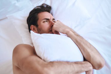 Man lying in bed holding pillow