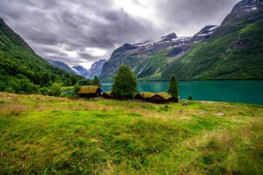 An old farm by the verdigris green lake Lovatnet, Norway clipart