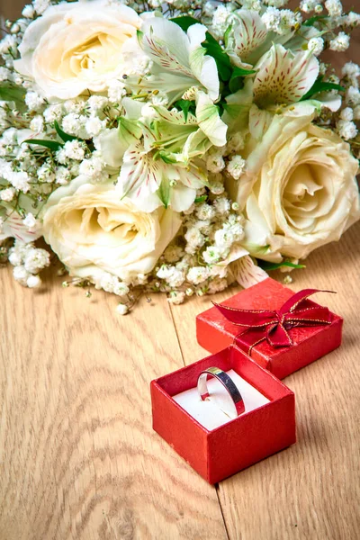 赤いギフトボックスのシルバーリング 木製の背景に白い花の花束 — ストック写真