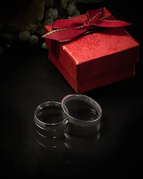 2つの白い金の結婚指輪 赤いギフトボックスの暗い背景に位置しています 接近中だ 選択的焦点 ぼかし わずかなノイズ — ストック写真
