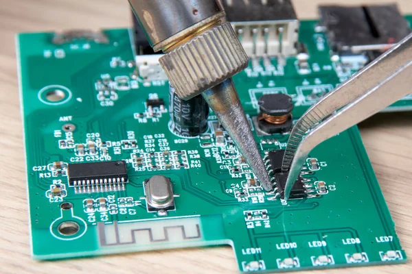 Electronic circuit board repair by replacing the damaged part with a soldering iron, electronic circuit board repair with soldering iron and tin wire, computer equipment, mobile phone, electronics, repair, upgrade and technology repair concept.