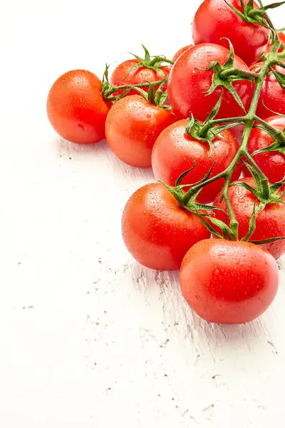 stock image Ripe cherry tomatoes with water drops on white wooden surface in the upper right corner of the photo. Vertical orientation of the photo. Close-up of cherry tomatoes. High quality photo