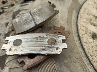 Yıpranmış fren pedleri araçtan çıkarılmış, sürtünme katmanındaki aşınma derecesi ve metal hasar açıkça görülüyor.