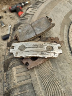 Yıpranmış fren pedleri araçtan çıkarılmış, sürtünme katmanındaki aşınma derecesi ve metal hasar açıkça görülüyor.